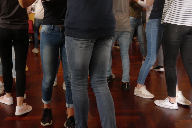 Jugendliche auf dem Tanzboden, wobei man nur die Beine sieht, die in Jeans stecken sieht und die Sneaker