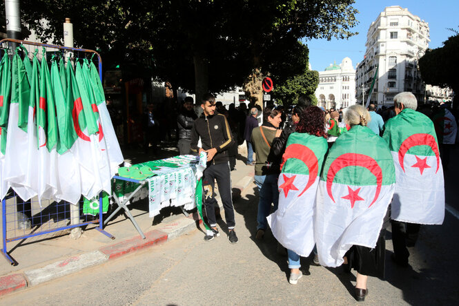 Ein Straßenhändler verkauft Algerischen Flaggen bei Protesten.