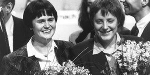 Christine Lieberknecht und Angela Merkel mit Blumensträußen auf einem historischen Schwarzweißfoto.