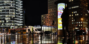 Ein mensch steht im Regen am Potsdamer platz und fotografiert mit dem Handy