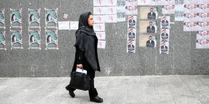 Eine Frau läuft Wahlplakaten entlang
