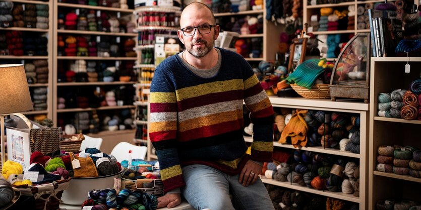 Sascha Uetrecht mit buntem Strickpulli in seinem Berliner Wollladen