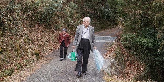 Zwei älteren Menschen gehen auf einem Weg.