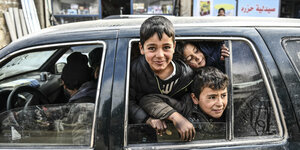 Kinder schauen aus einem Auto bei der Flucht aus Idlib.