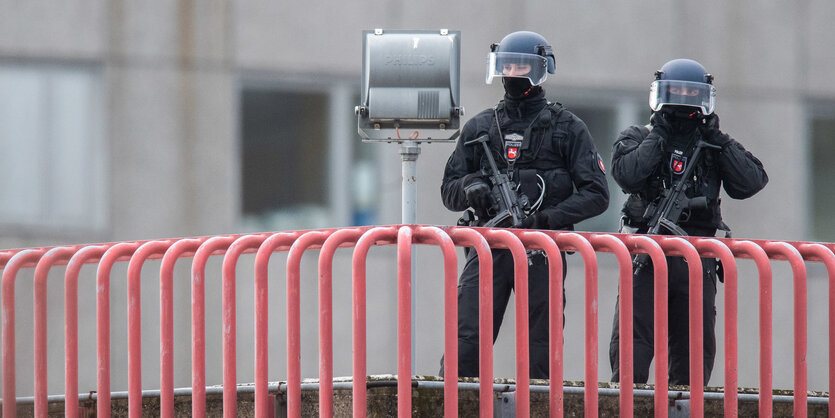 Zwei schwer bewaffnete Polizisten auf einem Dach.