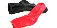 Eine schwarze und eine rote Socke liegen vorne an den Zehen übereinander