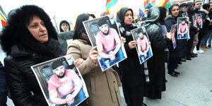 Mehrere Demonstrantinnen stehen in einer Reihe und halten das Porträt eines der Mordopfer in ihren Händen