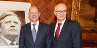 Olaf Scholz und Peter Tschenstscher stehen neben einer überdimensionalen Helmut-Schmidt-Briefmarke