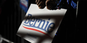 Ein Mensch hält ein Plakat auf dem Bernie steht, es fällt dunkler Schatten darauf