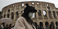 Eine Frau mit Mundschutz läuft am Kolosseum vorbei