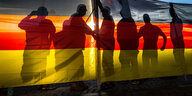 Die Schatten von Pegida-Anhänger werden im Gegenlicht in den Deutschlandfahnen sichtbar