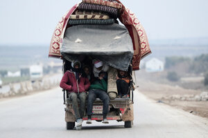 Menschen auf einem beladenen Fahrzeug bei der Flucht aus Idlib