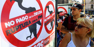 Passanten schauen sich Protestplakate an: "Nein, zur Zahlung von Auslandsschulden"