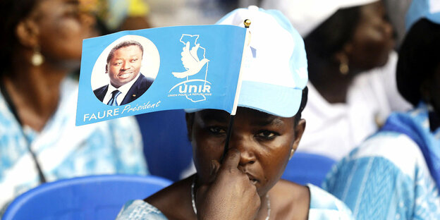 Eine Frau hält sich auf der Wahlveranstaltung von Faure einen Wimpel vors Gesicht Gnassingbé