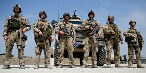 Sechs Soldaten stehen in einer reihe vor einem Panzer