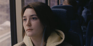 Die Schauspielerin Sidney Flanigan ist in einem Bus zu sehen.