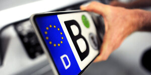 Ein Nummernschild mit einem B wie Berlin wird von einem Auto abnontiert