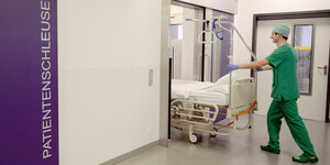 Ein Pfleger schiebt ein Krankenbett in einen Raum