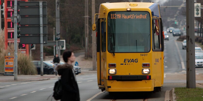 Eine Frau läuft über die Straße. Im Hintergrund ist eine Straßenbahn zu sehen