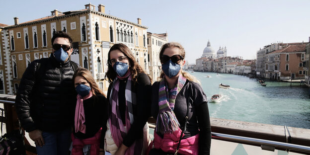 Touristen mit Atemschutzmasken auf einer Brücke in Venedig. Touristen mit Atemschutzmasken auf einer Brücke in Venedig.