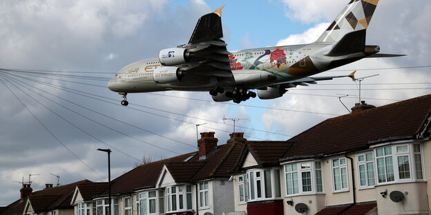 Eine Airbus A380-Maschine fliegt knapp über die Dächer eines Wohnviertels