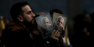 Ein Mann hält zwei Portraits von Soleimani in der Hand