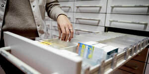 Eine apothekerin greift in einer apotheke in eine Medikamentenschublad