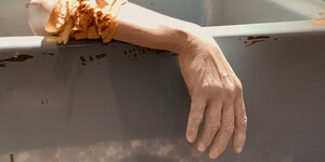 Der Arm eines Mannes hängt über den Rand einer Badewanne. Mehr ist von ihm nicht zu sehen. Standbild aus Rithy Panhs Film