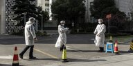 Beamte in Schutzanzügen kontrollieren eine Einfahrt in Shanghai
