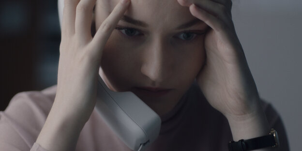 Eine Frau am Telefon stützt sich den Kopf mit den Händen.