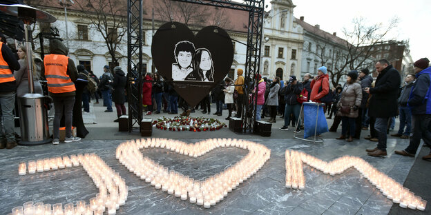 Menschen gedenken auf einem Platz Jan Kuciak und seiner Freundin. Viele Kerzen sind auf dem Boden zu einem J, einem Herzen und einem M formiert worden