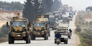 ein Militärkonvoi fährt eine Straße entlang