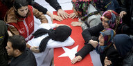 Frauen stehen aneinem Sarg mit einer türkischen Fahne und weinen