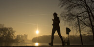 Ein Mann läuft bei Sonnenaufgang an der Rummelsburger Bucht entlang