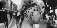 Junge Frau hat sich die Parole "Weg mit §218" auf die Kopfhaut geschrieben