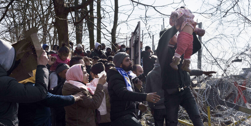 Geflüchtete an der türkisch-griechischen Grenze vor Stacheldraht.