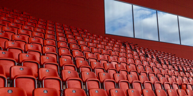 Eine rote leere Tribüne ine einem Fußballstadion mit Fenster