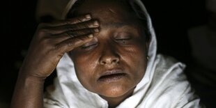 Eine Frau mit geschlossenen Augen, das Gesicht von einem Bildschirm beleuchtet