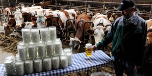 Bauer mit Bier, daneben Milchkrüge und Kühe