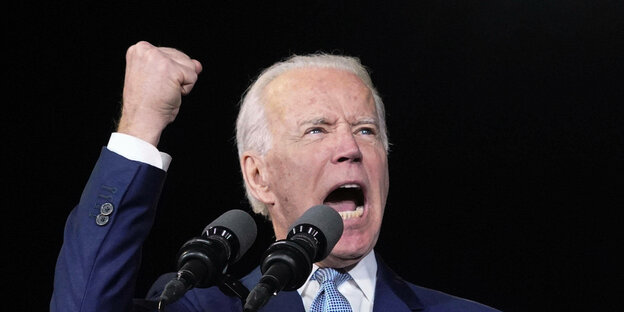 Joe Biden gestikuliert vor Mikrofon.