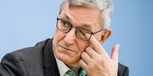 Bernd Riexinger reibt sich bei einer Pressekonferenzmit einem Finger ein Auge.