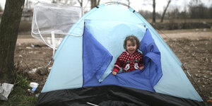 Kind schaut aus einem blauen Zelt heraus