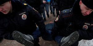 Ein Demonstrant wird von zwei Polizisten weggetragen