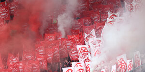 Ein Stadio voller roter FC Bayern Fahnen, und Rauch
