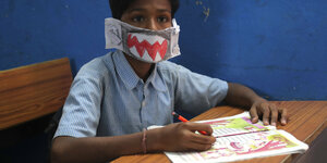 Ein Schüler in Indien mit einer selbstgebastelten Maske.