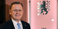 Bodo Ramelow vor rosa Hintergrund mit Thüringer Staatswappen