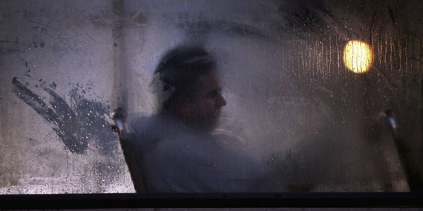 Ein Mann sitzt hinter einer beschlagenen Scheibe im Bus