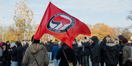 Menschen schwenken eine rote Fahne mit Antifa-Logo