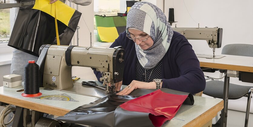 Eine Frau näht Taschen in einer Werkstatt