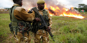 Zwei Ranger bewachen brennendes Elfenbein mit Gewehren